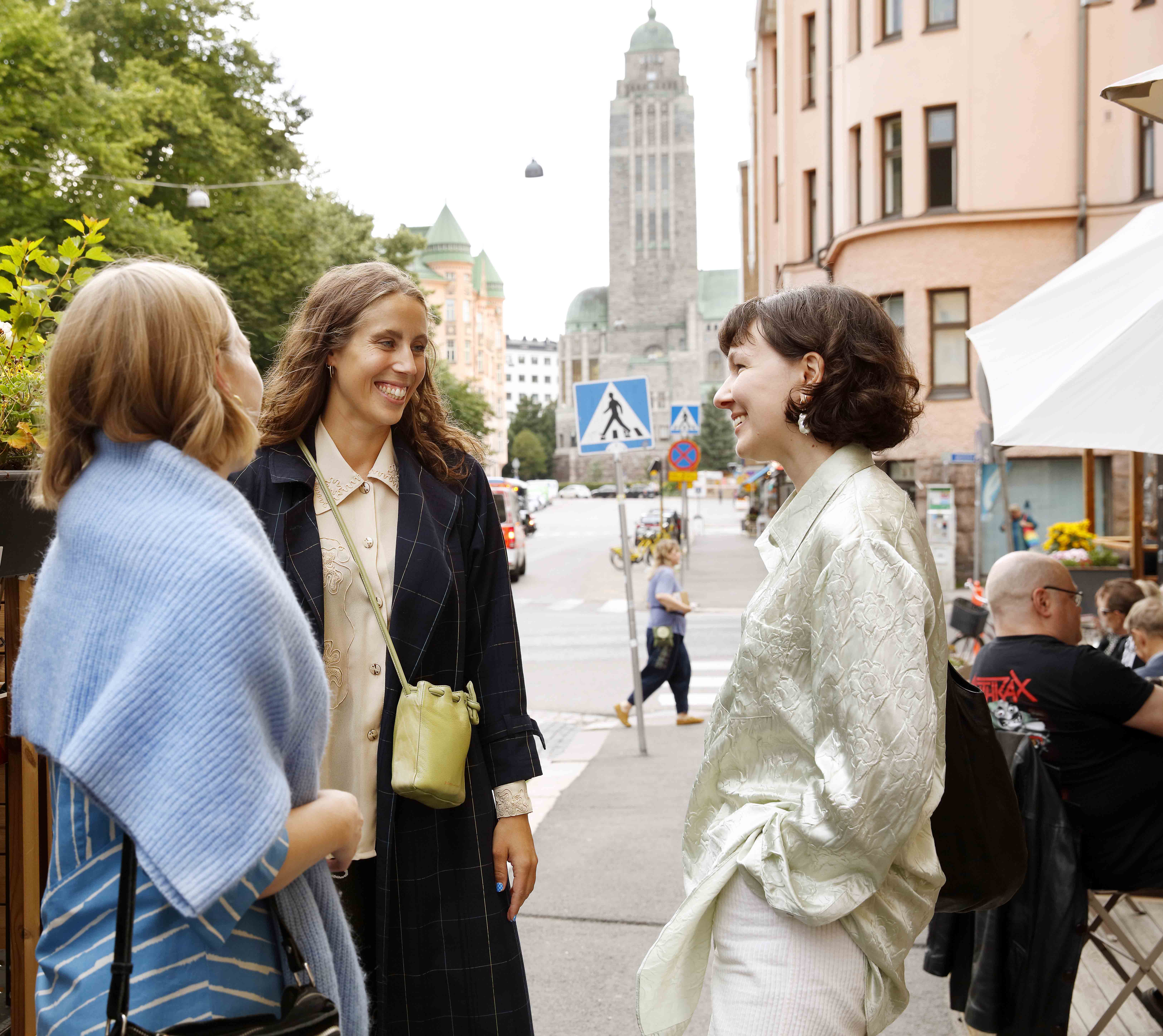 Three girls discussing on Helsinki streets.